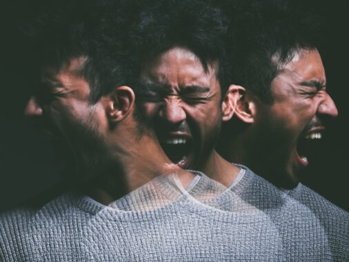 Studio shot of a young man experiencing mental anguish and screaming against a black background