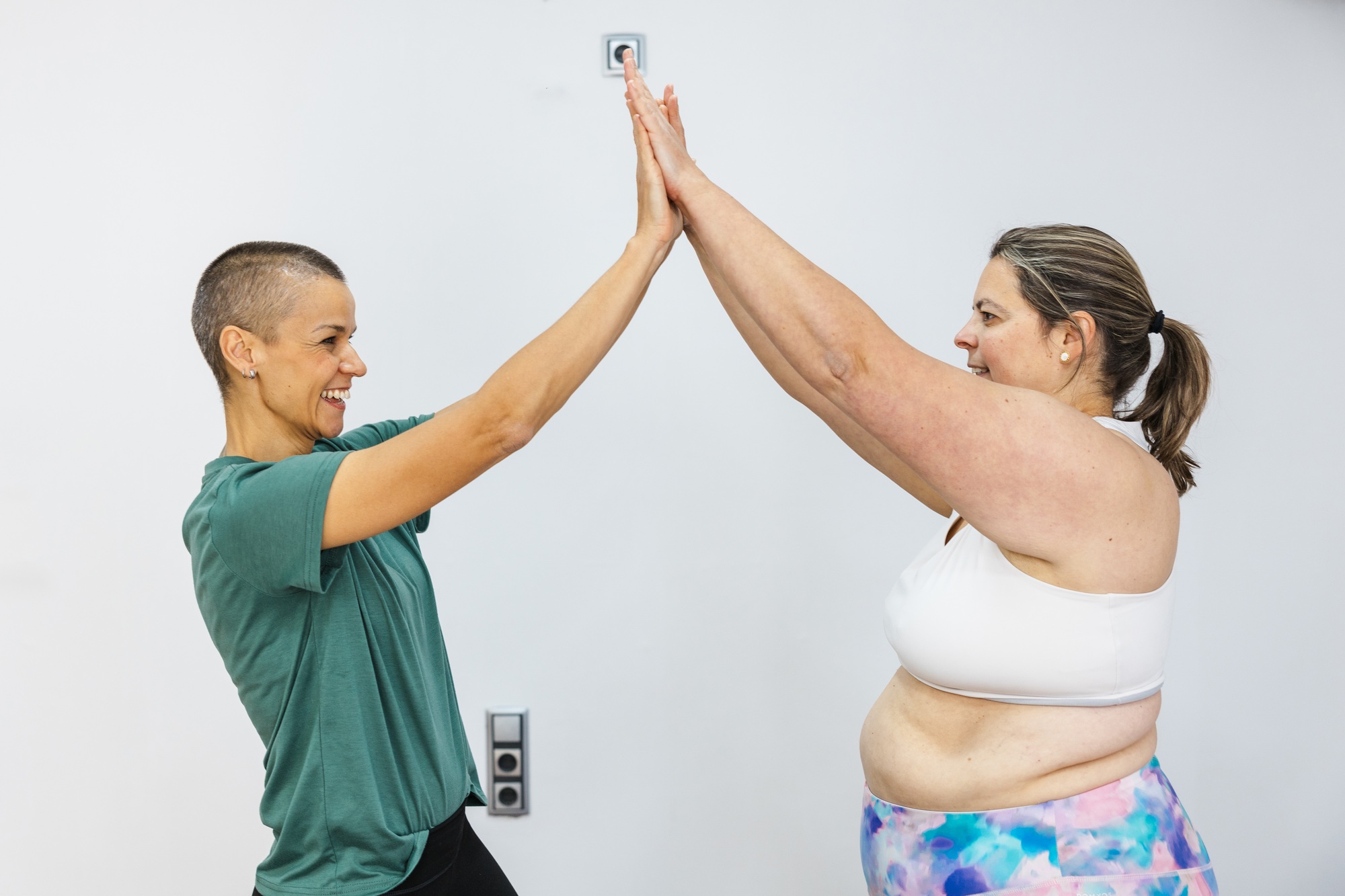 Personal trainer giving high five to overweight client celebrating weight loss